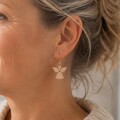 Kvinde med elegante engleøreringe i egetræ fra By Sandager. Små lette træøreringe med guldfarvet ørekrog og englemotiv – danske designøreringe perfekte som gave eller til jul.