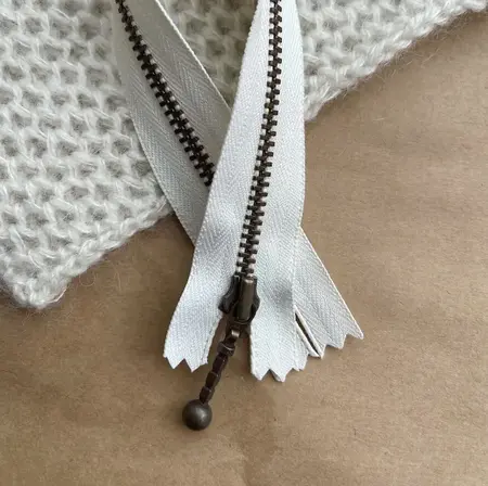 petiteknit zipper laengde 23 cm farve perlemor zipper ligger paa et bord