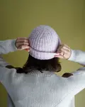 Model iført Vinga hue fra kit couture strikket i blow garn farven lyserød