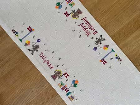 Close up af Broderet Fødselsdagsløber fra pomp stitch med flag og gaver og små figurer