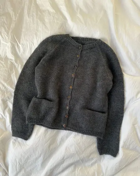 Copenhagen Cardigan i mørkegrå, strikket i Alpaca 2 og Silk Mohair, fotograferet fladt med synlige lommer og knapper.