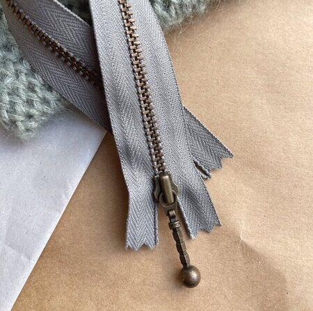 petiteknit zipper laengde 23 cm farve flint zipper ligger paa et bord