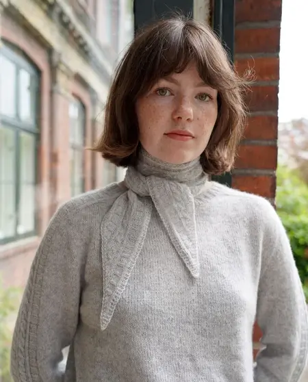 Model iført Strikket Sandoy tørklæde fra kit couture. Strikket i cashmere farven lys grå garn fra kit couture
