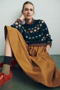 model sidder op af vaeg ifoert moerk udgave af gunta sweater fra helga isager