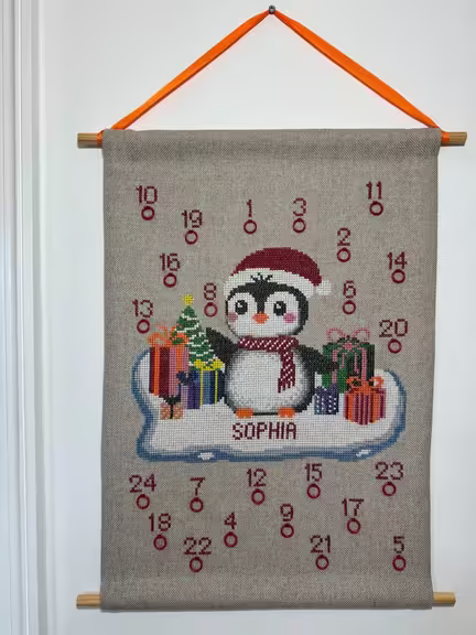 Pingvin-julekalender broderikit fra pomp stitch: pingvin på isflage med pakker og juletræ, broderet på Floba-stof.