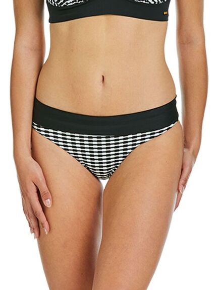 En kvinde iført sort- og hvidternede bikinitrusser med ensfarvet sort linning, vist fra midt på torsoen til øverst på lårene.