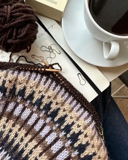 Strikkearbejde med PetiteKnit maskemarkører, pæreformede markører i guld og sølv brugt i mønsterstrik med kaffe og garn ved siden af