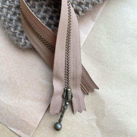 petiteknit zipper laengde 23 cm farve hasselnoed zipper ligger paa et bord