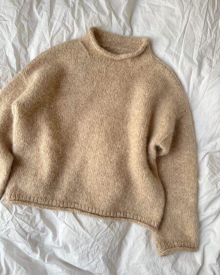 petiteknits cloud sweater i beige soft og silk mohair fra isager ligger på seng