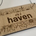 skilt i trae med blomster og teksten er i haven