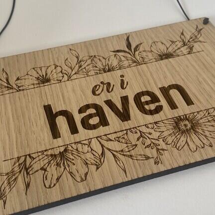 skilt i trae med blomster og teksten er i haven