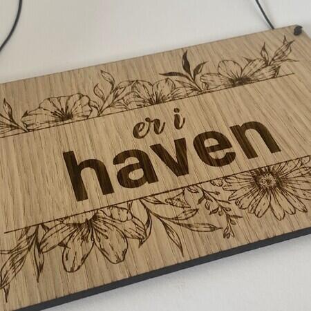 skilt i trae med blomster og teksten er i haven