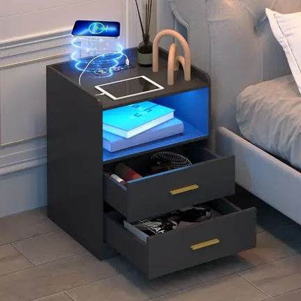 Et moderne natbord med åbne skuffer, med oplyste hylder med elektronik, bøger og et abstrakt indretningsstykke. En digital projektion svæver over og viser futuristisk grafik. Opstillingen er ved siden af en seng på et trægulv.