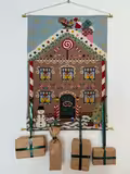 Broderet adventskalender fra pompstich gingerbread hænger på væg med 4 pakker