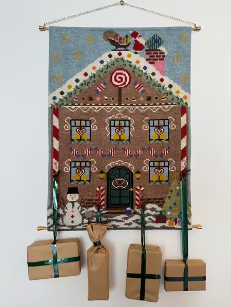 Broderet adventskalender fra pompstich gingerbread hænger på væg med 4 pakker