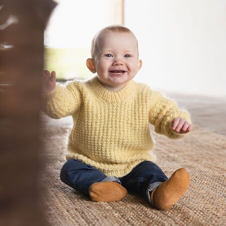 baby ifoert gul zahle sweater fra filcolana han smiler til kameraet