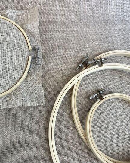 Sæt af bambus-broderiringe i flere størrelser lagt på naturfarvet lærred – metalspænde synligt øverst.