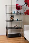 En moderne sort reol med glashylder mod en creme væg. Den rummer små dekorative vaser, et indrammet foto, et blåt glas og en skål. En del af en hvid lænestol og et farverigt blomstermaleri er synlige i nærheden.