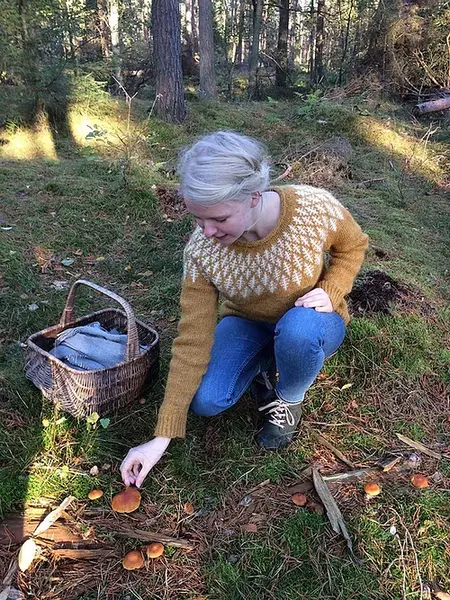 model sidder paa hug i skoven ifoert hanne rimmens prisme sweater