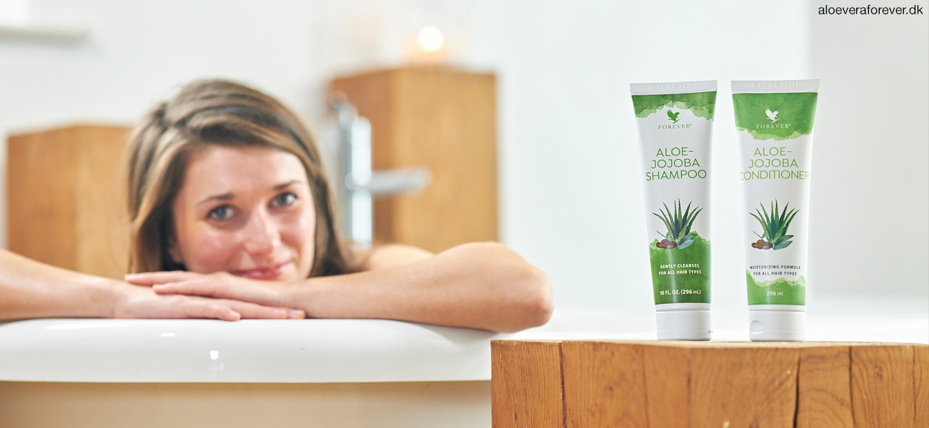Aloe Jojoba Shampoo og Aloe-Jojoba Conditioner på skammel ved siden af badekar med kvinde