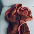 helga isagers strikket model lone cardigan ligger paa en sofa