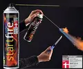 En person bruger en lang lighter til at antænde en spray fra en Startfire-dåse, hvilket producerer en kontrolleret blå flamme. Dåsen har et rødt og sort design med flammer og et schweizisk flagsymbol. Et prismærke er synligt i hjørnet.
