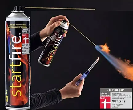 En person bruger en lang lighter til at antænde en spray fra en Startfire-dåse, hvilket producerer en kontrolleret blå flamme. Dåsen har et rødt og sort design med flammer og et schweizisk flagsymbol. Et prismærke er synligt i hjørnet.
