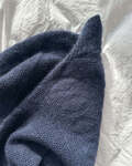 esther sweater model paa sengen foldet sammen petiteknit strikket i blaa version