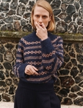 Mikala Sweater i navy og rosa mønster stående foran murværk – set forfra.