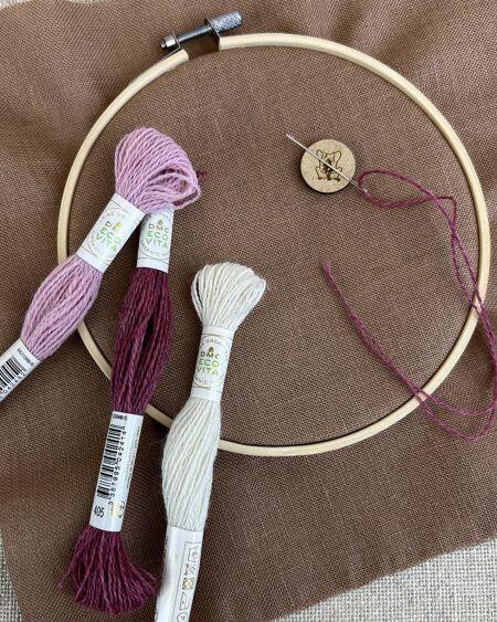 Broderiring i bambus med brunt stof, nål og DMC Eco Vita broderigarn i rosa og naturfarver – klar til broderi.