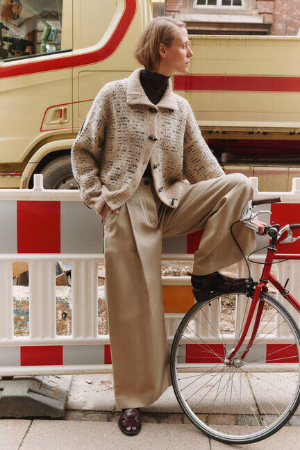 Ava Jacket fra My Favourite Things Knitwear stylet på model – oversize strikjakke i sandfarvet alpaca- og tweedmix med avismønster og duffelknapper.