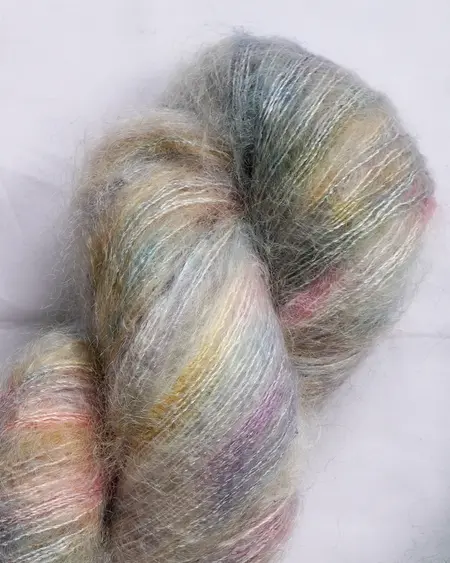 Close up af håndfarvet Kidsilk Garn fra Cowgirlblues x Kit Couture: Farve Hilma lys hvid og regnbuefarver
