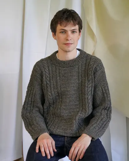 Model iført Strikket Sandoy sweater Mand fra kit couture. Strikket i mørk beige tweed garn fra kit couture