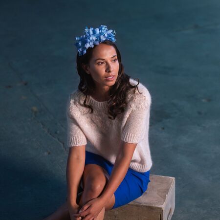 model sidder og folder haenderne om knaene ifoert daysi strikket bluse fra hanne rimmen og filcolana