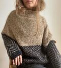 Kvinde iført Jeol Sweater af Aegyoknit med sandfarvet bærestykke og mørkegråt mønster på krop og ærmer.