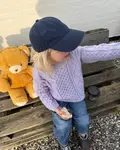 Barn iført Dagmar Sweater Junior fra PetiteKnit strikket i Peer Gynt – sweater i strukturstrik