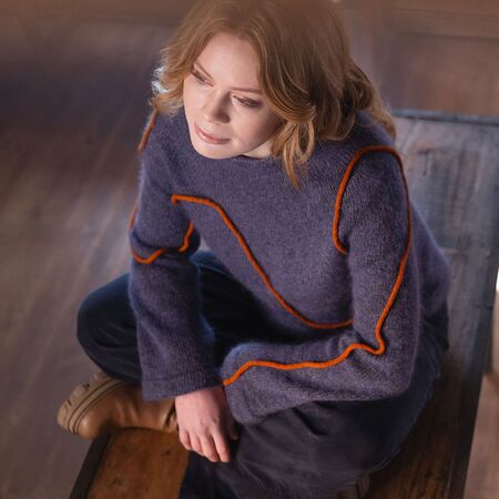 model i fugleperspektiv sidder paa en stol ifoert breaking free sweater fra filcolana