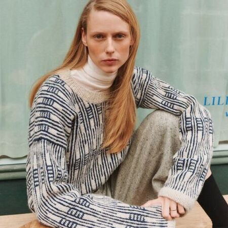 model siddende ved cafébord Grace Sweater fra wieseknit – grafisk sweater i mønsterstrik, en del af Isager Archives 2