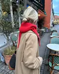 Sophie Hood fra PetiteKnit i rød Eco Cashmere Vintage, båret over lys frakke, set bagfra i bymiljø.