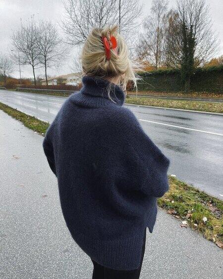 Ryggen af Højgravid Mette Vendelbo/Petiteknit står på vej i sin mørkeblå Chestnut Sweater