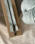 petiteknit zipper i farven havskum 17 cm på bord