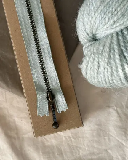 petiteknit zipper i farven havskum 17 cm på bord