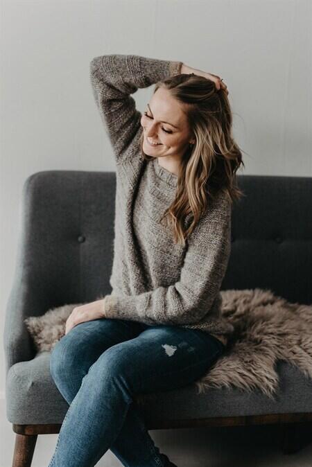 kvinde sidder i sofa iført sin basic sweater fra camarose i grå