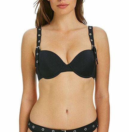 En kvinde iført en sort bikini med øskener på stropperne og i linningen står på en hvid baggrund.