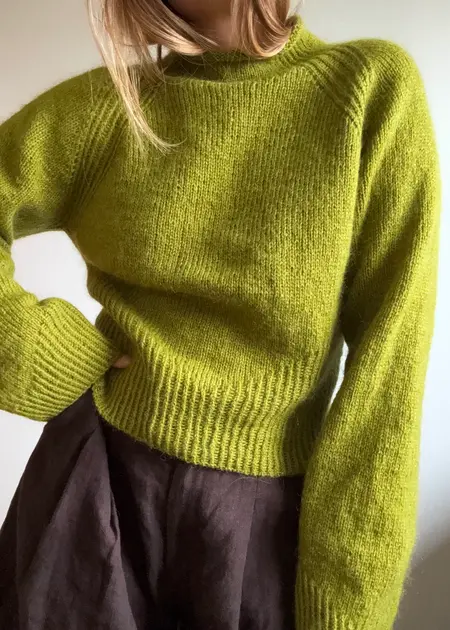 Model iført Isa raglan strikket i limegrøn Saga og Tilia fra Filcolana