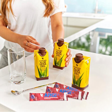 Kvinde tilbereder GelARGI+ Tri-Pak med Forever Aloe Vera Gel og ARGI+ sticks