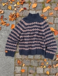 Mikala Sweater lagt fladt på brosten med efterårsblade omkring – navy og rosa mønster