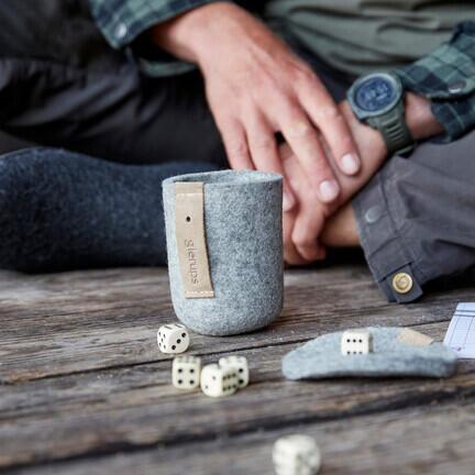 close up af folk som spiller yatzy med glerups raflebaeger paa bordet