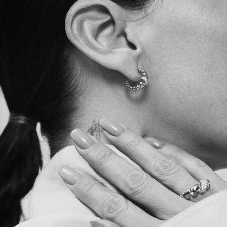 Medina iført SWIRL W. TOPAZ øreringe i sølv med hvid topas.