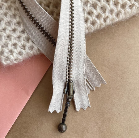 petiteknit zipper laengde 23 cm farve sand zipper ligger paa et bord